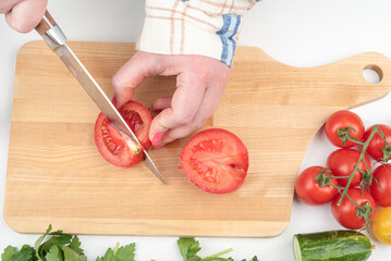 Cutting with a knife will not edible part of the tomato on the cutting board.