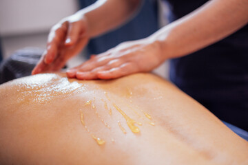 Massage of the cervical collar area with honey. The female client lies on the table and gets a back...