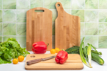 Kitchen table with cutting boards and a set of vegetables for salad.