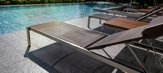 Picture of a sun bed chair on the edge of a hotel or resort rooftop swimming pool - obrazy, fototapety, plakaty