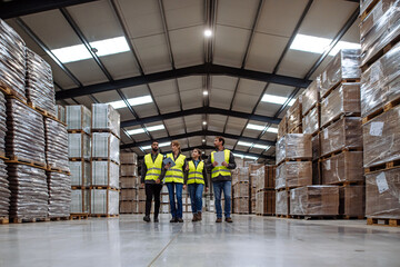 Front view of warehouse workers walking in warehouse. Team of warehouse workers preparing products...