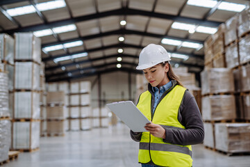 Female warehouse worker reading product order, order picking. Warehouse manager checking delivery,...