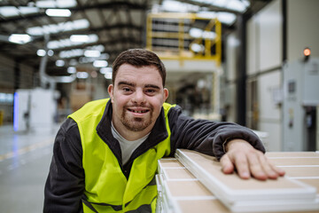 Portrait of young man with Down syndrome working in warehouse. Concept of workers with...