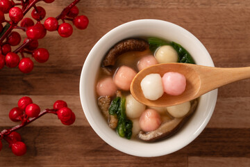 Eating red and white small tangyuan with savory soup and vegetable for lunar new year festival.