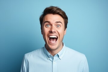 Portrait of a young surprised man on blue background. Emotions
