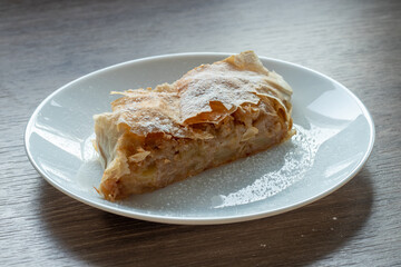 Fresh Hungarian apple strudel on a white plate on the kitchen counter