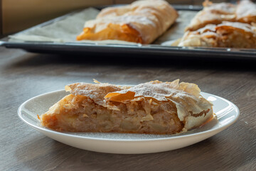 Fresh Hungarian apple strudel on a white plate on the kitchen counter