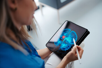 Portrait of female doctor sitting in office, looking at test results CT scans in tablet. Female...