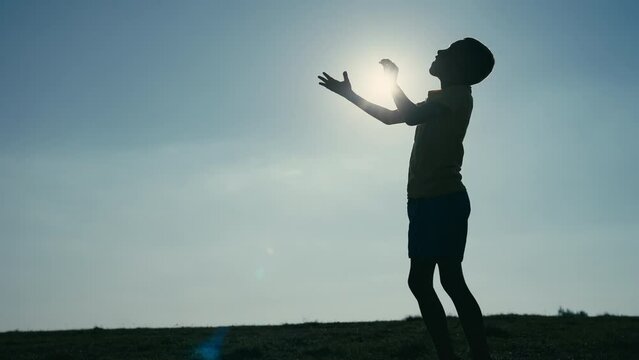 Kid Throwing a Ball and Catching It in a Shillouette as Sun Shines Above Him. Concept of Future Athlete, Summer Olympics, Paris 2024, Dream