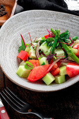 Salad of fresh tomatoes, cucumbers, onions and vegetables in a gray bowl, close up, selective focus