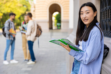 Asian long-haired girl with a notebook in the college yard