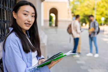 Asian long-haired girl with a notebook in the college yard