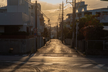 正面に太陽のある夕焼けの街の直線の道