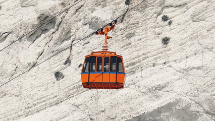 Orange funicular car against the background of  white rock - obrazy, fototapety, plakaty