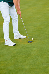 An unrecognisable man plays golf on a manicured professional golf course.