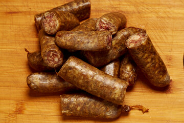 Homemade sausages cut into pieces placed on a wooden chopper.