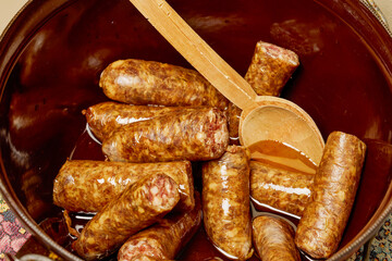 Pieces of homemade sausage in a pot with cooking oil.