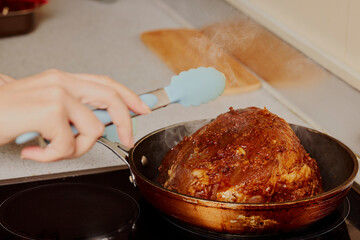Piece of pork neck in a pan on an electric stove.