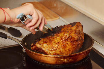 Piece of pork neck in a pan on an electric stove.