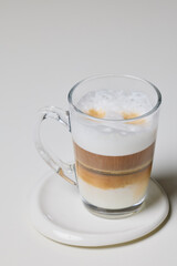a transparent mug with Cappuccino on a table.