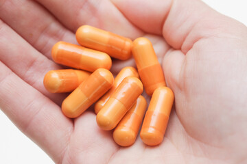 Female hand holding pills. Woman open hand with medicine. Drugs isolated on white background. Orange vitamin capsules on girl hand. Cutout hand holding diet supplement.