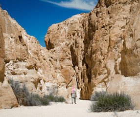 bedouin in white goes in the canyon in the desert among the rocks in Egypt Dahab South Sinai