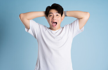 Portrait of Asian guy posing on blue background