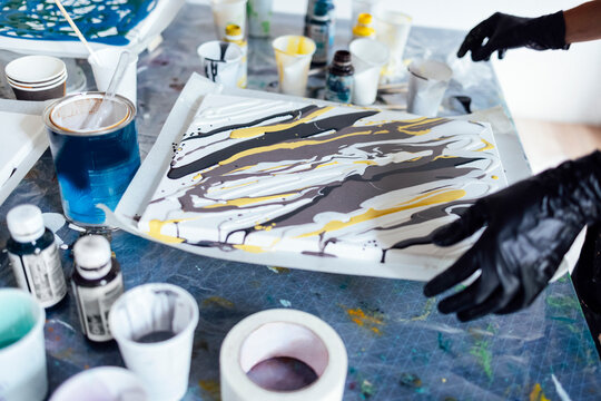 Painting tutorial. Young white girl in the gloves paint with liquid acrylic in an art workshop