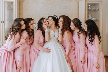 Portrait of the bride with her friends in the room. A brunette bride in a long white dress and her...