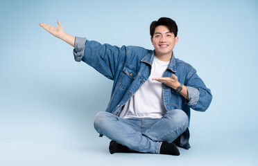 Full body image of Asian guy posing  on blue background