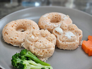 Ground meat dog food in donut and dog paw shape with carrot and broccoli