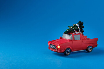 Fototapeta na wymiar A small red toy with a green Christmas tree on the roof, on a blue background