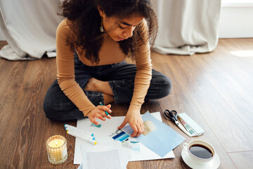 Young brunette african american woman creating her Feng Shui wish map using scissors