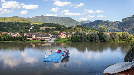 Fototapeta na wymiar a ferry on the river carrying people and car to the other side of the river Vah, Kompa Strecno, Slovakia