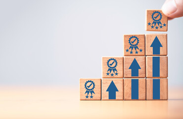 Hand holding the best quality guarantee symbol on the top of wooden stacking with up arrow for...
