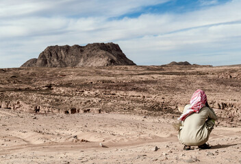 lonely bedouin sits and waits in the desert in egypt