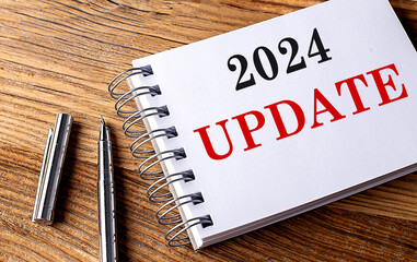 2024 UPDATE text on notebook with pen on wooden background