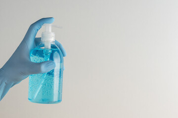 Hand in medical glove with hand sanitizer in a bottle on white background. Coronavirus prevention concept.