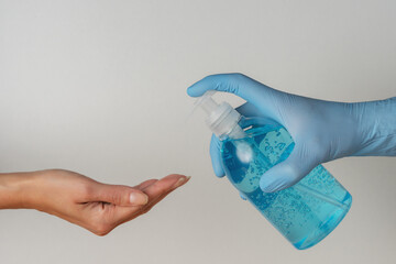 Hand in medical glove with hand sanitizer in a bottle on white background. Coronavirus prevention...