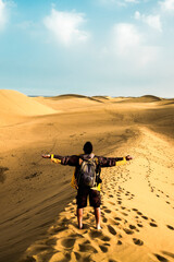 Fototapeta na wymiar Standing man back view open arms and enjoy with wild beautiful desert in front - lifestyle and adventure trekking backpack travel vacation people concept - alternative summer holiday trip for people