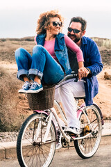 Joyful love friendship concept - happy adult caucasian, couple having fun with bicycle in outdoor...