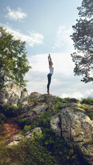 Woman practicing yoga on top rocky mountain