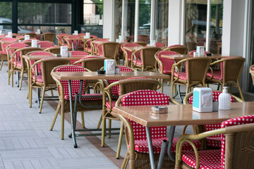 A lot of empty wooden chairs in red white plaid fabric and tables in cafe.