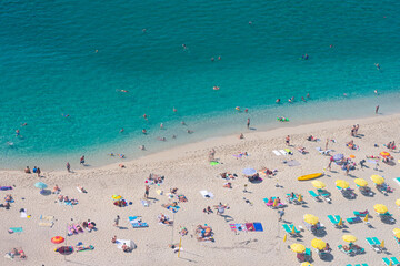 Beautiful top view of blue sea ocean water and beach shore with lots many of people tourists in summertime and bright sunlight sun.Tourism destination,vacation,holiday