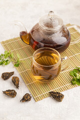 Red tea with herbs in glass on gray concrete. Side view.