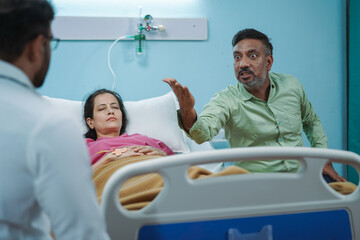 Shoulder shot, angry patient husband scolding or arguing with doctor at hospital ward - concept of...