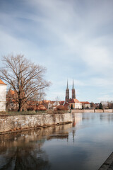 view of an old church and a large tree across the city canal in Wroclaw, in sunny weather