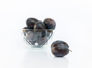 Plum in the foreground and in a glass bowl isolated on white