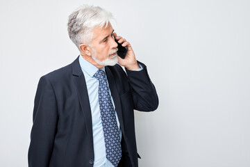 Portrait of elderly businessman in suit talking on mobile phone. Person with smartphone isolated on white background.