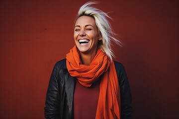 Portrait of a beautiful young woman laughing against a red wall.
